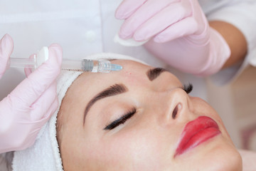 The cosmetologist makes the facial injections procedure for tightening and smoothing wrinkles on the face skin of a beautiful woman in a beauty salon.Cosmetology skin care.