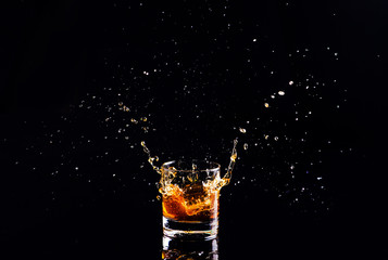 whiskey with splash on black background, brandy in a glass