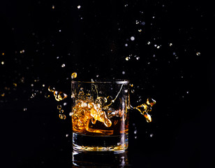 whiskey with splash on black background, brandy in a glass