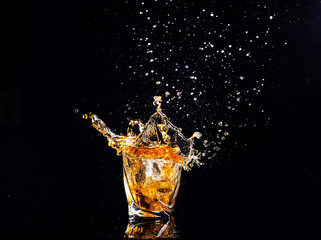 whiskey with splash on black background, brandy in a glass