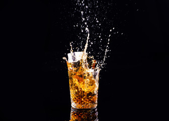 whiskey with splash on black background, brandy in a glass
