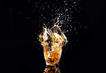 whiskey with splash on black background, brandy in a glass
