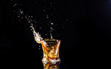 whiskey with splash on black background, brandy in a glass