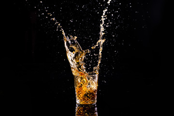 whiskey with splash on black background, brandy in a glass