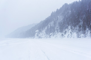 valley of a winter river during a snowstorm