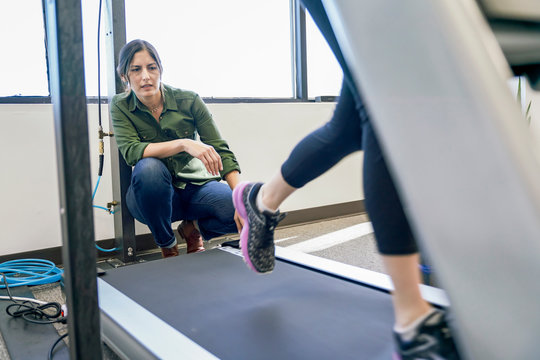 Physiotherapist examining her patient during exercising on treadmill