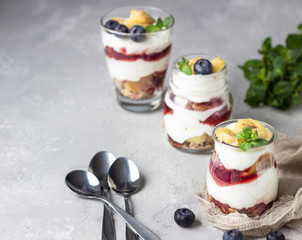 Granola, blueberry and banana greek yogurt parfaits in mason jars. Healthy breakfast. A light grey concrete background. Copy space.