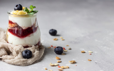 Granola, blueberry and banana greek yogurt parfaits in mason jars. Healthy breakfast. A light grey concrete background. Copy space.