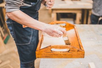 Manual processing of wood in the carpentry workshop - applying varnish on the product