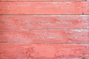 The texture of the wooden wall is red with peeling paint