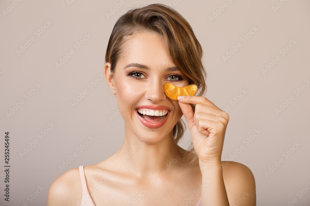 Wall mural Happy woman using eye applicator mask.