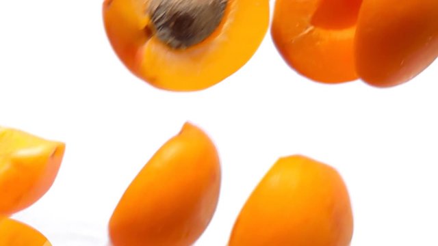 Halves ripe apricots fly close-up on white background in slow motion