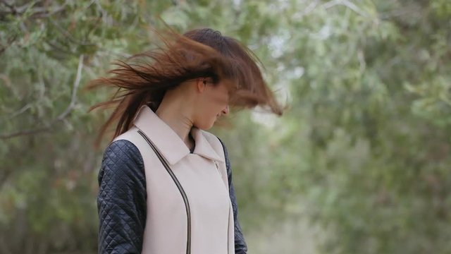 strong wind wawing hair of the beautiful young woman in the park. Nature background