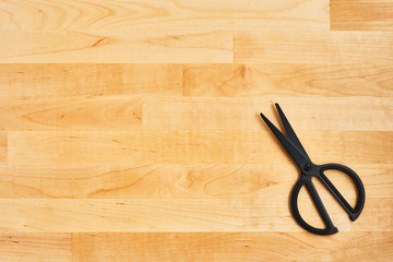 Black scissors on yellow wooden background. Top view. Copy space for text or design.