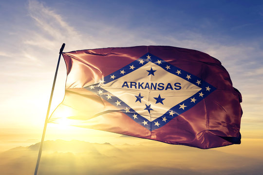 Arkansas state of United States flag waving on the top sunrise mist fog