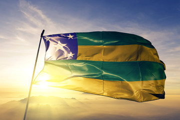 Sergipe state of Brazil flag waving on the top sunrise mist fog - obrazy, fototapety, plakaty
