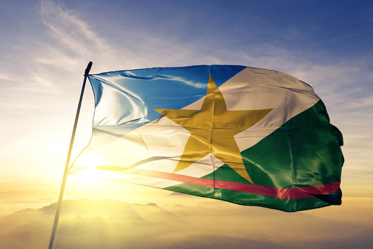 Roraima state of Brazil flag waving on the top sunrise mist fog