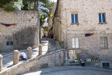 Fototapeta na wymiar Tourists walking in the streets of San Marino and a street artist painting