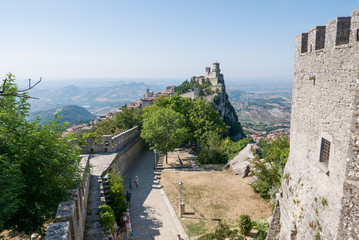 Fototapeta na wymiar Guaita tower in the fortifications of San Marino on Monte Titano, with the City of San Marino on the left.