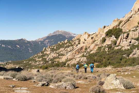 Hikers walking in a path in La Pedriza, National Park of mountain range of Guadarrama in Manzanares El Real, Madrid, Spain.
