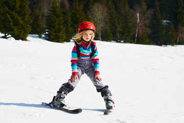 Fototapeta na wymiar Child girl skiing in mountains. Active kid with safety helmet and goggles. Ski race for young children. Kids ski lesson in alpine school. Little skier racing in snow