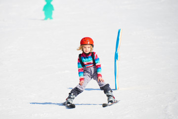 Fototapeta na wymiar Child girl skiing in mountains. Active kid with safety helmet and goggles. Ski race for young children. Kids ski lesson in alpine school. Little skier racing in snow