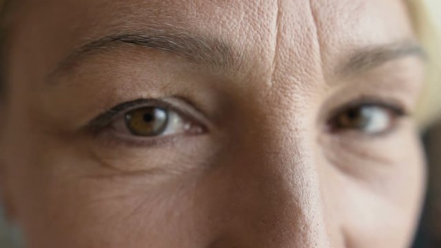 Close-up of caucasian mature woman's face with dark eyes and visible aging wrinkles