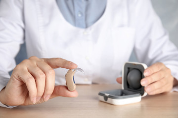 Doctor with hearing aid at table, closeup