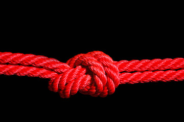 Red rope with knot on black background