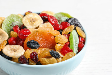 Bowl with different dried fruits on wooden background, closeup. Healthy lifestyle