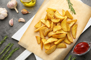Delicious baked potato wedges on grey background, flat lay