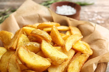 Delicious baked potato wedges on parchment paper, closeup