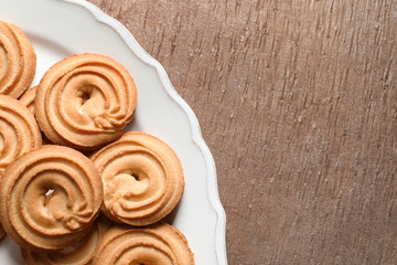 Plate with Danish butter cookies on wooden background, top view. Space for text