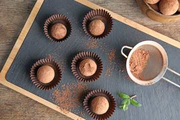 Board with chocolate truffles on wooden background, top view