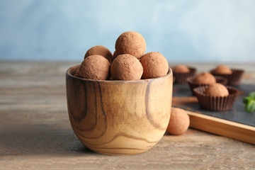 Bowl with chocolate truffles on wooden table