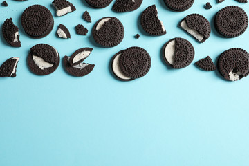 Tasty chocolate cookies with cream on color background, flat lay. Space for text