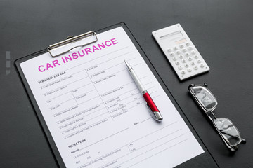 Car insurance form near glasses, calculator, pen on black background