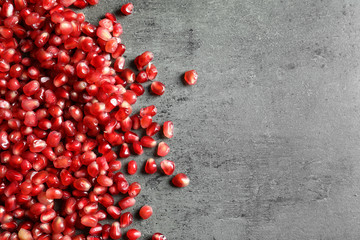 Pomegranate seeds on grey background, top view with space for text