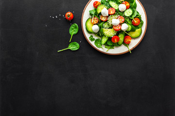 Healthy lunch. Fresh vegetable salad on black background top view copy space