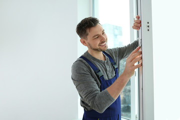 Construction worker installing plastic window in house