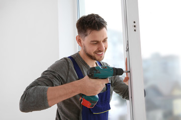 Construction worker using drill while installing window indoors