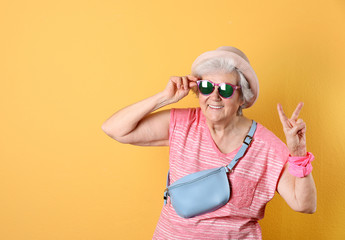 Portrait of cool grandmother on color background, space for text