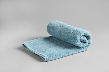 Fresh fluffy rolled towel on grey background