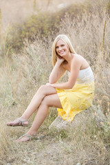 Beautiful young woman sitting in field legs crossed