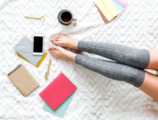 Girl top view with mobile phone, tea and notebook for work at home on bed background