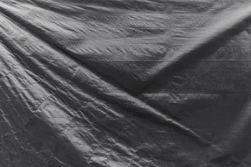 Full frame background of a wrinkled tarp texture in black and white.