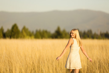 Young lady spinning in field looking over shoulder