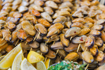 Appetizing skewers of mussels closeup.