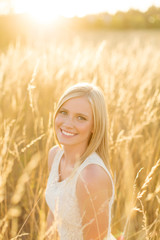 Beautiful girl sitting in sunny field smiling