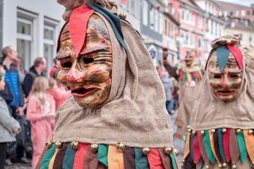 Shrovetide figure in brown costume walks sideways. Street Carnival in Southern Germany - Black Forest.